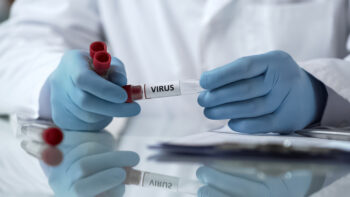Chemist holding virus vaccine tube, writing report of laboratory experiment