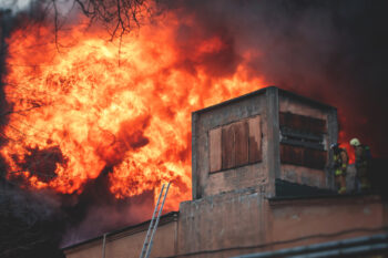 Massive large blaze fire in the city, brick factory building on fire, hell major fire explosion flame blast,  with firefighters team firemen on duty, arson, burning house destruction