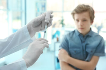 Hands of doctor preparing for vaccination and blurred patient on background