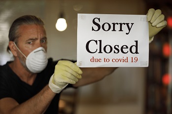 coronavirus closed for business concept, male business owner with medical mask puts sorry closed sign on window during covid 19 virus pandemic, cafe shop bankrupt, covid-19 restrictions and lockdowns